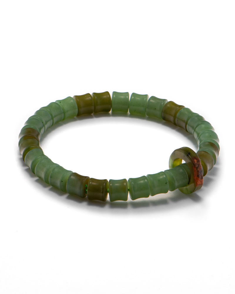 LYU_3812_1 Studio photo of a green Nephrite (soft jade) bracelet, featuring carved ring-shaped beads with deeper olive sections and a brownish-red accent ring, on a white background.