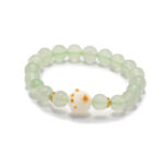 Studio photo of a light green Quartzite jade bracelet, featuring spherical beads with a spotted white center accent and subtle gold-tone spacers, on a white background.
