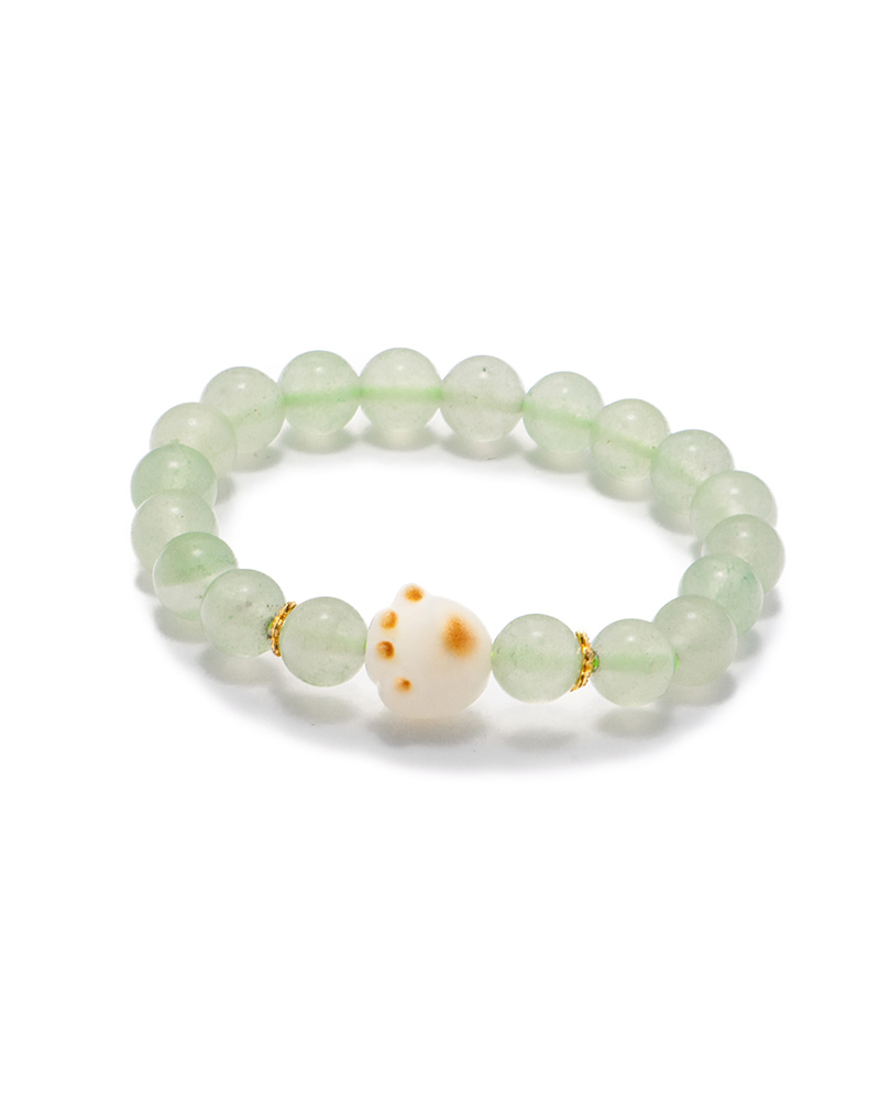 LYU_3822 Studio photo of a light green Quartzite jade bracelet, featuring spherical beads with a spotted white center accent and subtle gold-tone spacers, on a white background.