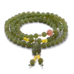 Grayish-green nephrite bead multi-wrap bracelet with carved focal element and warm translucent accents on a white background.