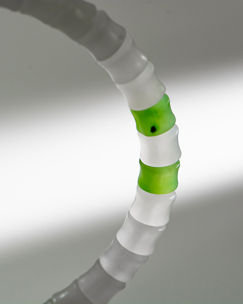 LYU_3894 A close-up of the Natural White Nephrite Jade Bracelet, featuring handmade translucent beads with alternating white and two green segments, set against a soft gray and white gradient background.