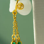 The Icy Green Tianshan Cui Chalcedony Bracelet features bamboo-knot beads and a white lucky pouch charm, displayed against a soft green background.