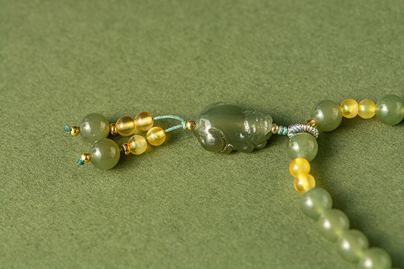 LYU_3985 Olive Green Nephrite Jade Wrap Bracelet features round beads and a central carved green bead; can be worn as a convertible necklace, shown here on an olive-green background.