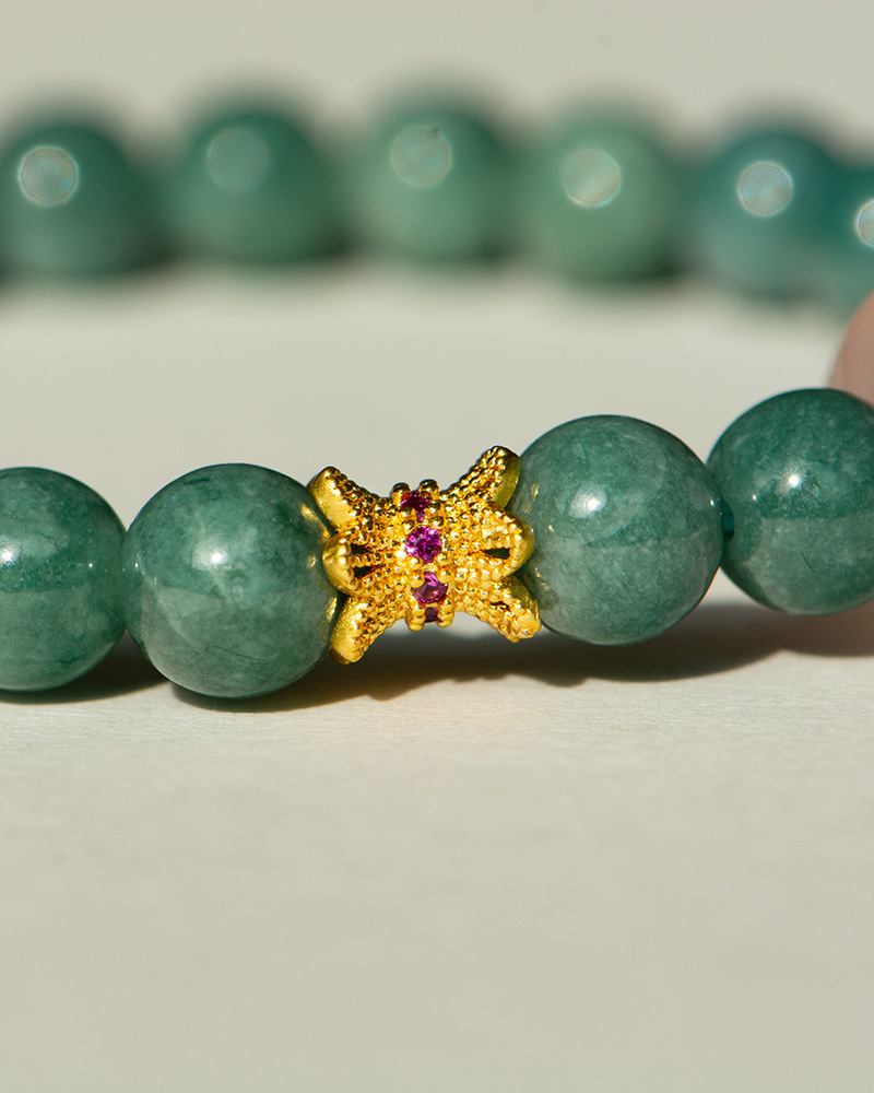 LYU_4009 A close-up of the Green Jadeite Bracelet featuring round green beads and a clear Buddha-head charm at the center.