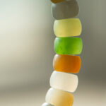 A close-up of the Pastel Spectrum Nephrite Jade Bracelet – Heishi Rondelles, featuring translucent, rounded beads in white, yellow, green, and orange against a blurred neutral background.
