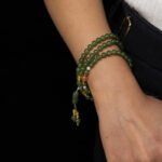 Someone wearing the Olive Green Nephrite Jade Wrap Bracelet – a stylish accessory with round beads that can also be worn as a convertible necklace.