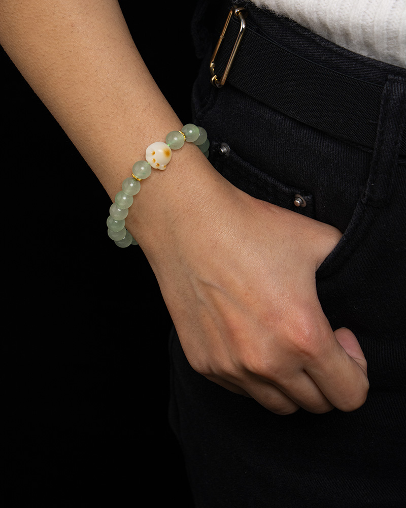 LYU_4249 A person in dark pants and a white top has a hand in their pocket, displaying the Mint Green Aventurine Quartz Bracelet with round beads and a cat paw charm.