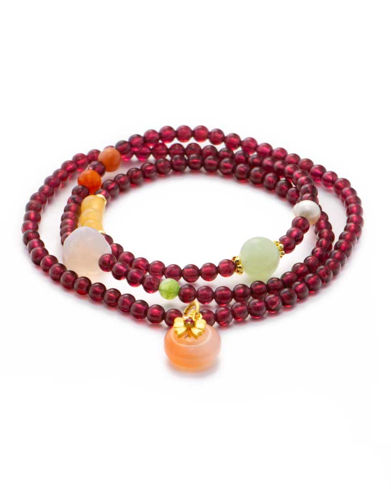 Purplish-red garnet multi-wrap bracelet with a peach-toned drop and warm gold accents on a white background.