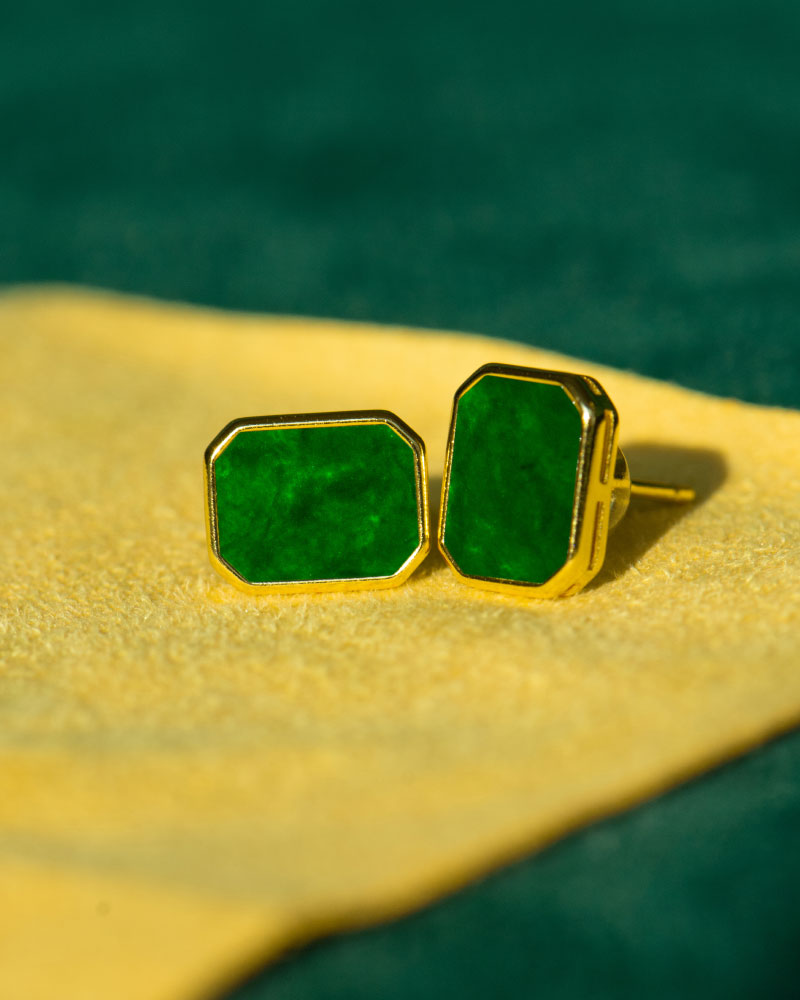 Vivid Green Jadeite Stud Earrings – Rectangular Flat Inlay, set in gold-plated 925 sterling silver, are displayed on yellow fabric with a green background.