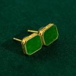 Vivid Green Jadeite Stud Earrings – rectangular flat inlay set in gold-plated 925 sterling silver, shown on a dark green textured surface.