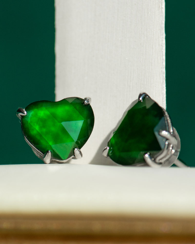 Vivid Green Jadeite Stud Earrings feature heart-cut stones with custom faceting, set in 925 sterling silver prongs, displayed against a white and green background.