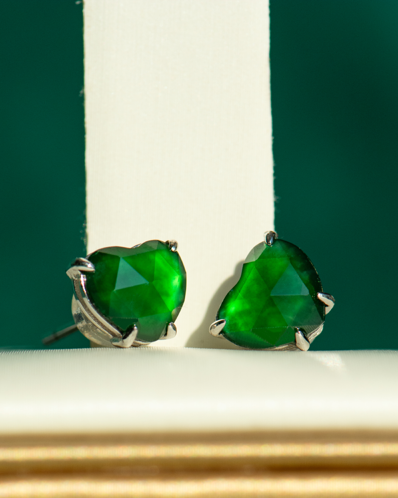 A pair of Vivid Green Jadeite Stud Earrings with heart-cut custom faceting in 925 sterling silver, displayed upright against a white and green background.