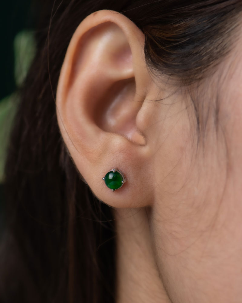 LYU_5204 Close-up of a person with straight brown hair tucked behind the ear, wearing Vivid Green Jadeite Stud Earrings – round cabochon beads in a silver setting.