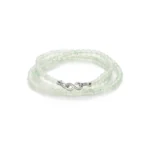 A delicate bracelet made of translucent, pale green beads with a silver infinity symbol clasp, coiled neatly on a white background.