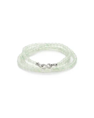 A delicate bracelet made of translucent, pale green beads with a silver infinity symbol clasp, coiled neatly on a white background.