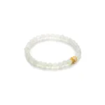 A beaded bracelet made of translucent white round beads with a small gold decorative charm, displayed on a white background.
