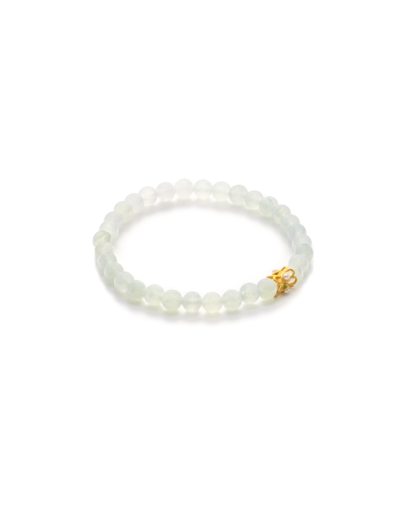 A beaded bracelet made of translucent white round beads with a small gold decorative charm, displayed on a white background.