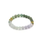 A round beaded bracelet made of polished stones in green, white, and lavender shades, with one yellow bead featuring a blue and red decorative design, displayed on a white background.