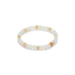 A beaded bracelet made of white and light yellow round stones, featuring one gold-colored bead with a small red accent, displayed on a white background.
