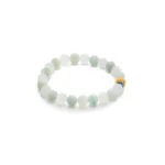 A beaded bracelet made of round, pale green jade beads with one distinctive gold bead featuring blue and red accents, arranged in a circle on a white background.