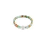 A beaded bracelet with small, round beads in shades of green, brown, orange, and blue, featuring a single larger white bead at the center.