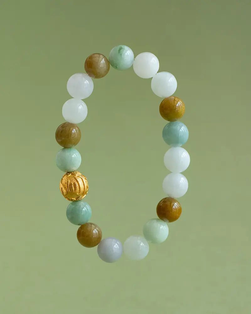DSC_0572 拷贝 A beaded bracelet with round stones in white, green, and brown hues, and one distinctive gold bead, displayed against a plain light green background.